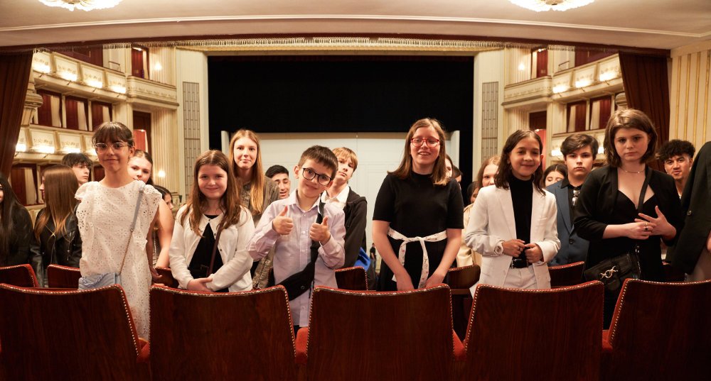Eine Gruppe von Mittelschüler:innen posiert lächelnd in der Mittelloge der Wiener Staatsoper.