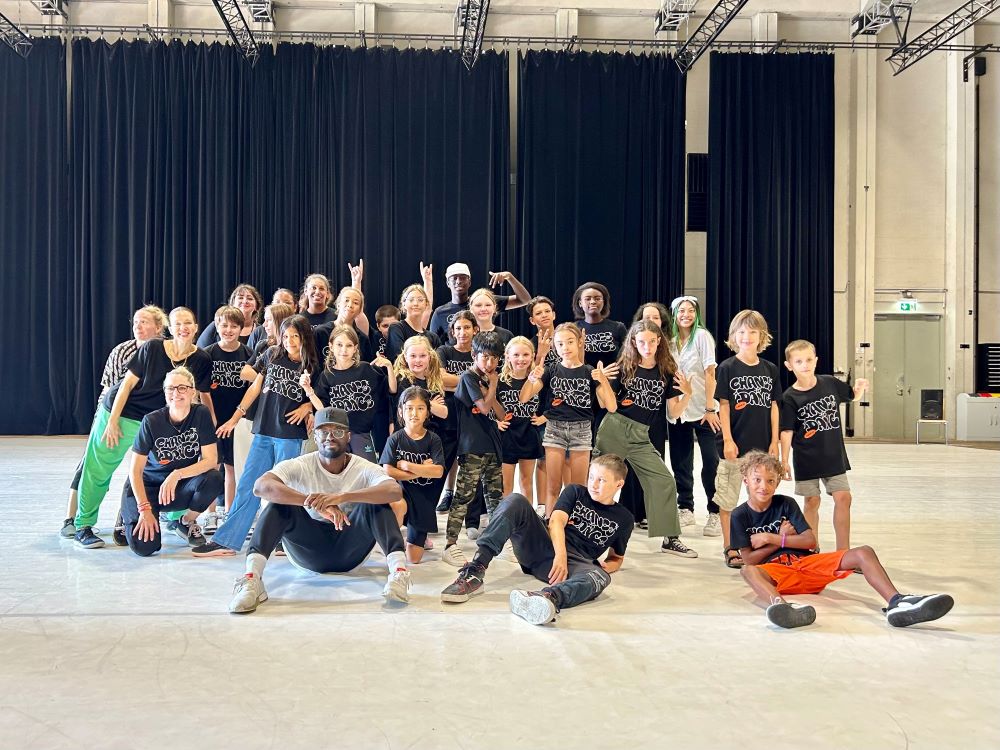 Eine Gruppe Kinder und Jugendlicher posiert für ein Gruppenfoto mit Jermaine Browne.