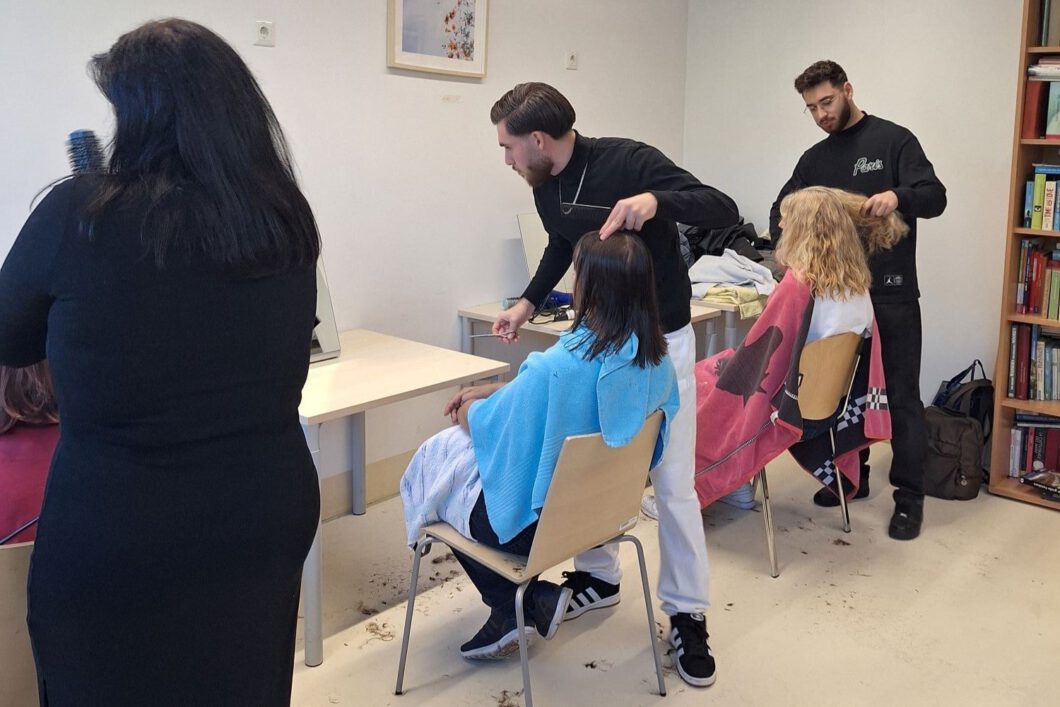 Zwei Frisöre schneiden die Haare von zwei Frauen.