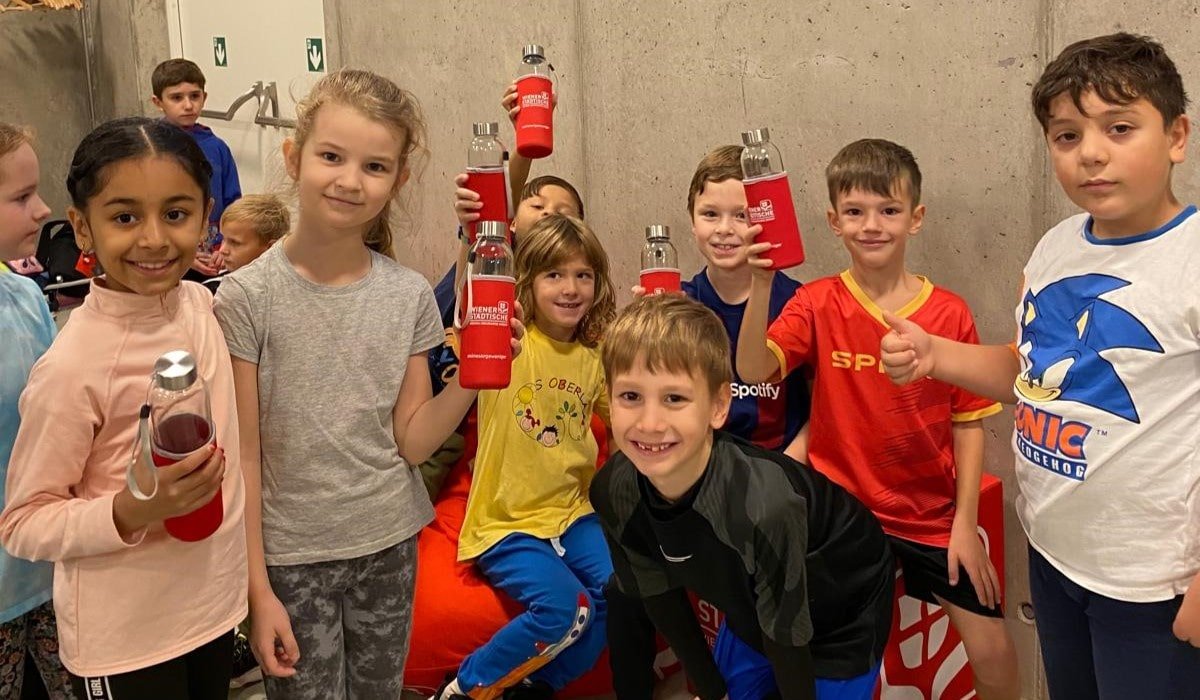 Eine Gruppe von Kindern posiert mit gebrandeten Trinkflaschen der Wiener Städtische Versicherung.