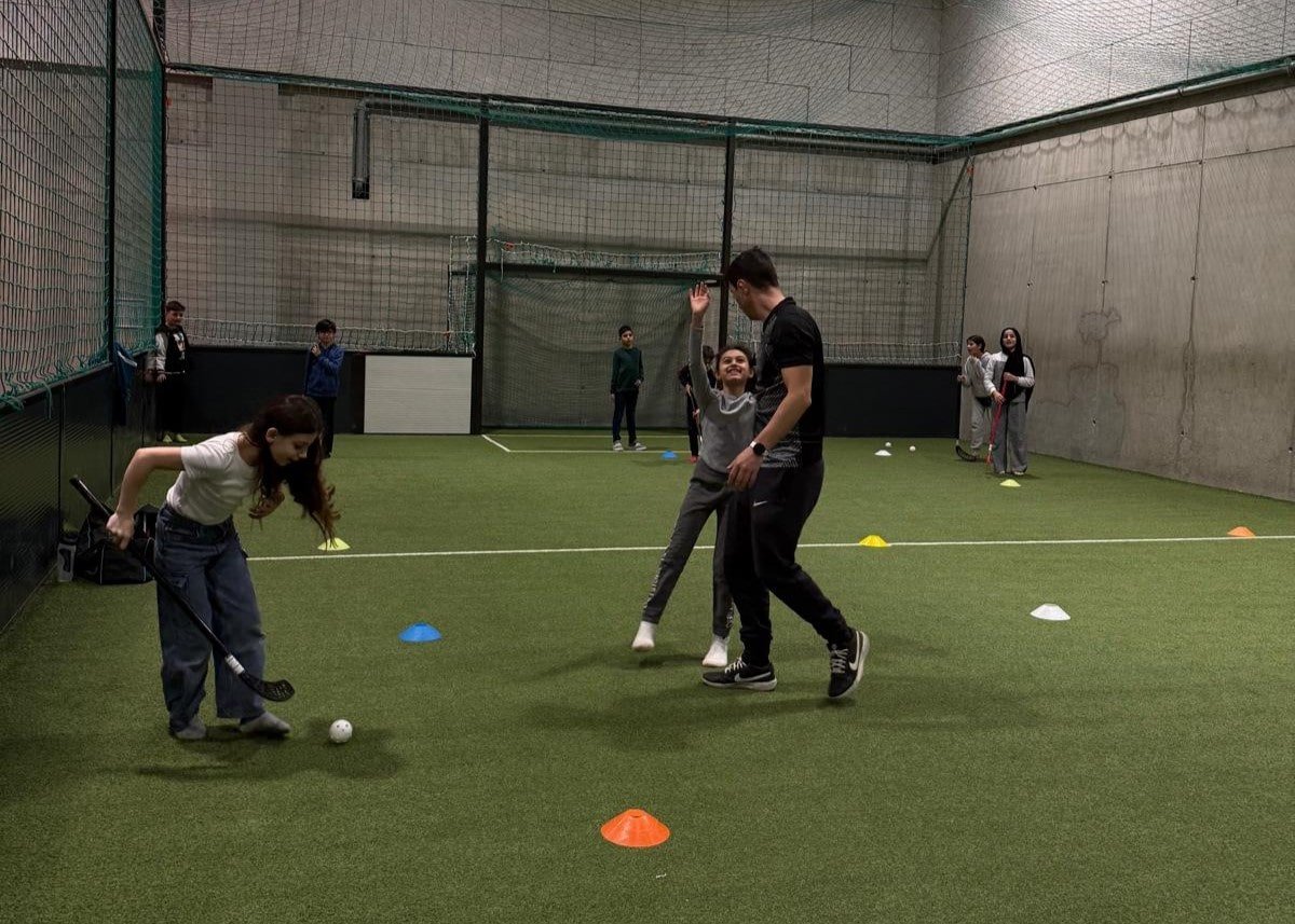 Eine Kinder spielen in einer Sporthalle Land-Hockey.