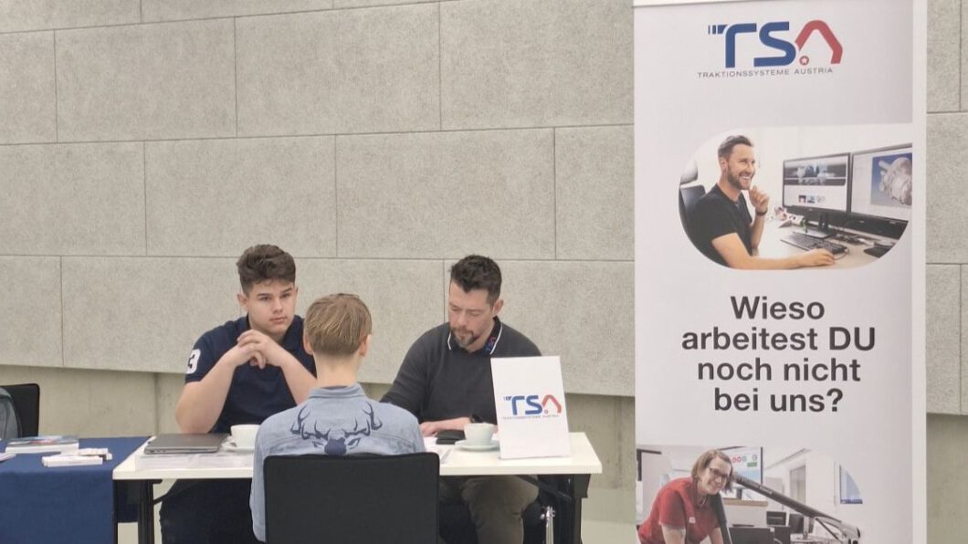 Ein Mitarbeiter und Lehrling von TSA sitzen gegenüber von einem Jugendlichen und führen ein Bewerbungsgespräch.