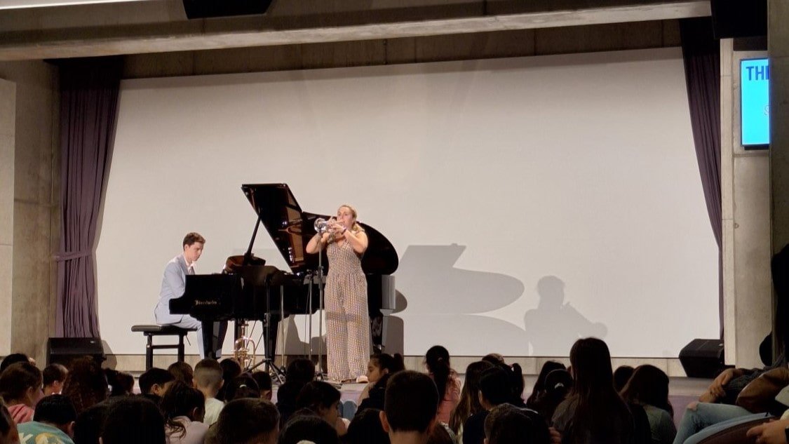 Ein Pianist und eine Trompeterin treten im CAPE 10 vor einigen sitzenden Kindern auf.