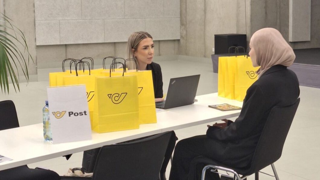 Eine Mitarbeiterin der Post und eine Jugendliche sitzen gegenüber an einem Tisch und führen ein Bewerbungsgespräch.