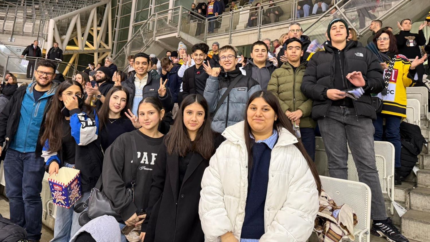 Eine Gruppe von Kindern posiert auf der Tribüne eines Eishockey-Stadiums.