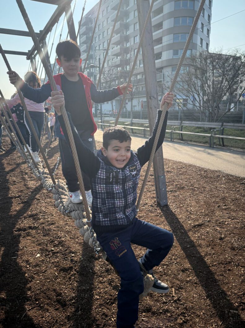 Zwei Buben balancieren auf einem Seil auf einem Kinderspielplatz. 