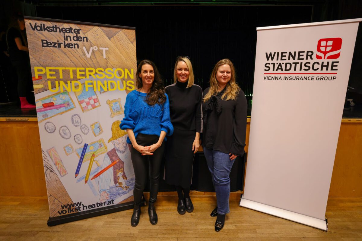 Michaela Seeböck, Silvia Bruni und Susanne Valoch posieren vor zwei Roll-Ups der Wiener Städtischen und des Volkstheater Wiens.