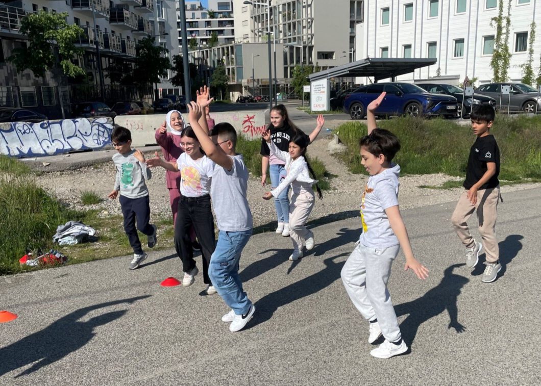 Eine Gruppe von Kindern führt eine Aufwärmübung im Freien aus.