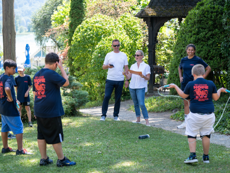 Ein Gruppe von Kinder springt Seil und Plasser & Theurer betreut die Station.