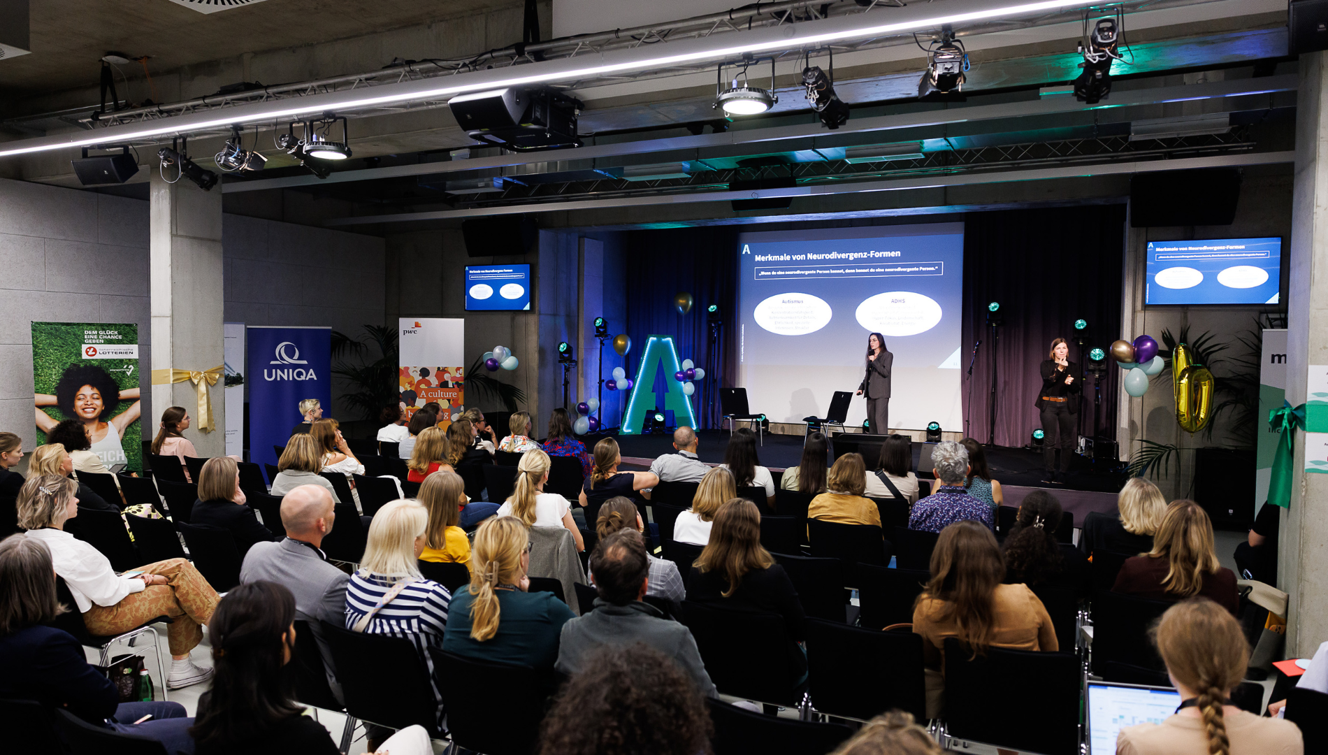 Eine Vortragende steht auf der Bühne im CAPE 10 und hält einen Vortrag im Rahmen des DisAbility Confidence Day 2024.