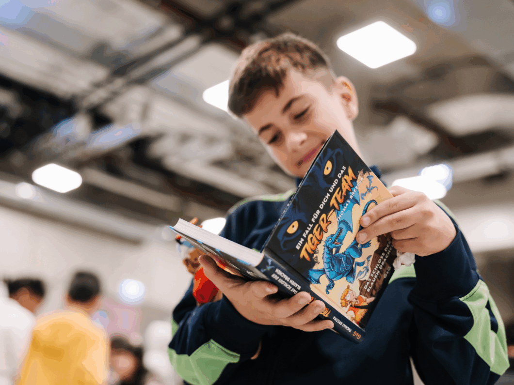 Ein Bub der Kinderbuchlesung mit dem geschenkten Tiger Team Buch.