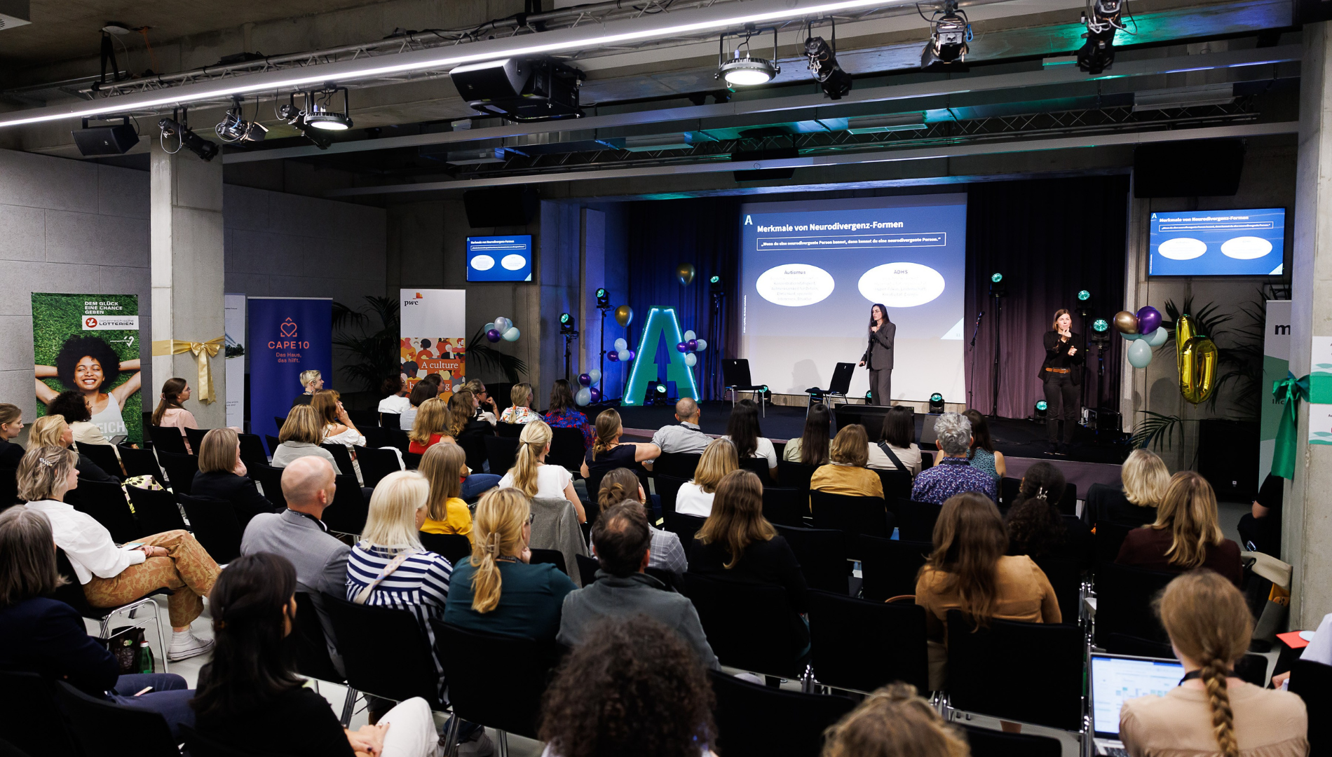 Eine Vortragende steht auf der Bühne im CAPE 10 und hält einen Vortrag im Rahmen des DisAbility Confidence Day 2024.