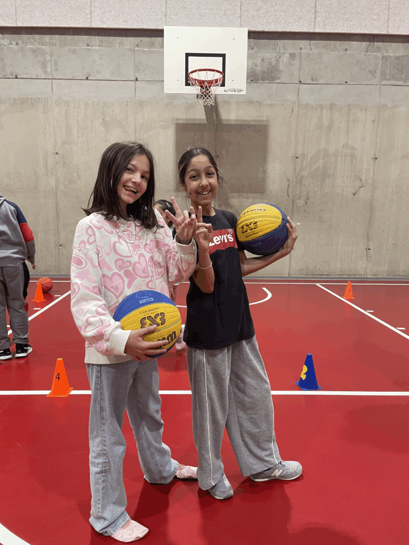 Zwei Mädchen posieren mit einem Basketball.