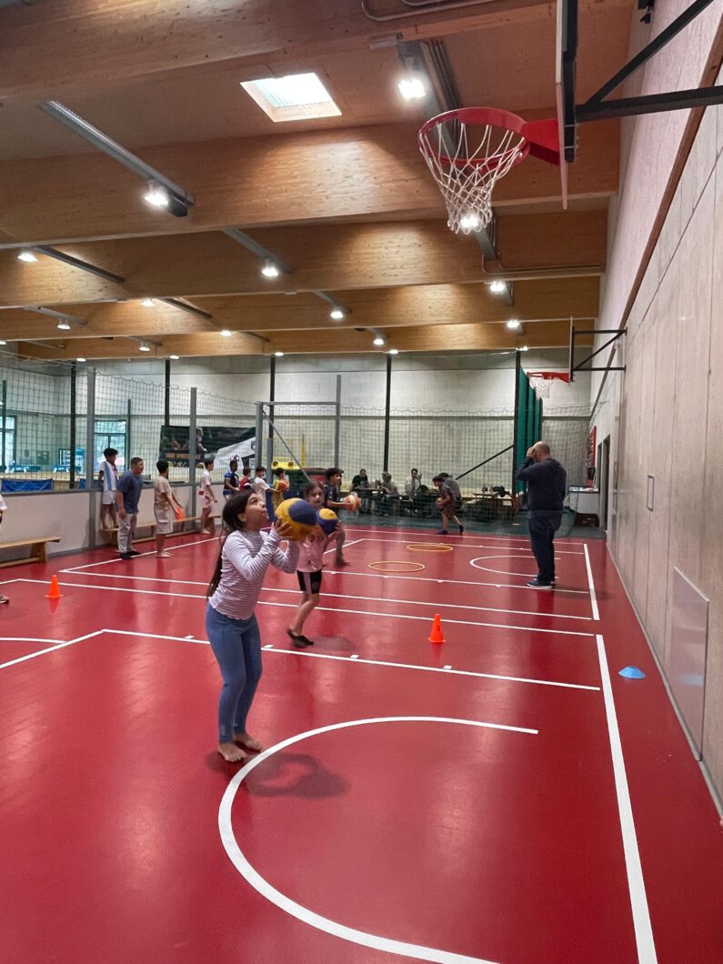 Mädchen wirft Basketball in einem Korb.