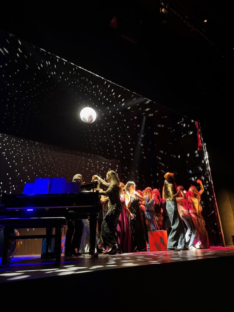 Einige Personen befinden sich tanzend auf einer Bühne.