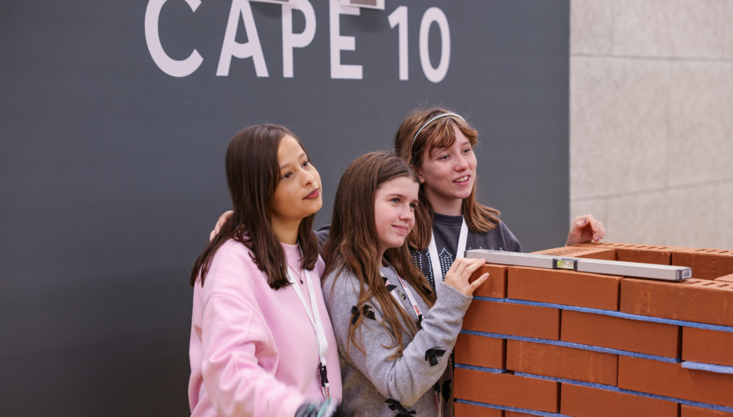 Drei Mädchen posieren lächelnd im Veranstaltungsaal von CAPE 10.