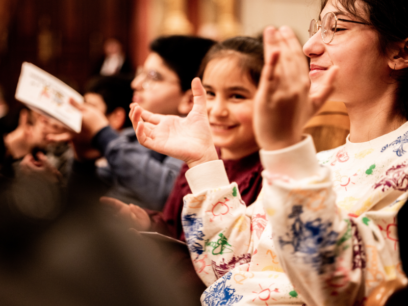 Mädchen klatschen lachend in den Zuschauerreihen des Musikvereins.