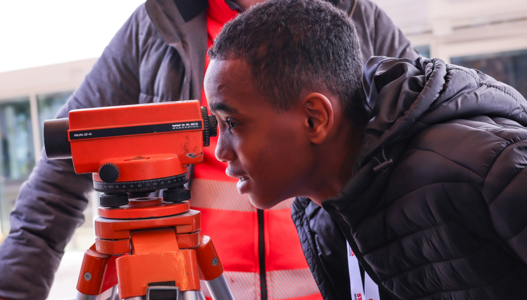 Ein Bub schaut durch ein Straßenvermessungsgerät.