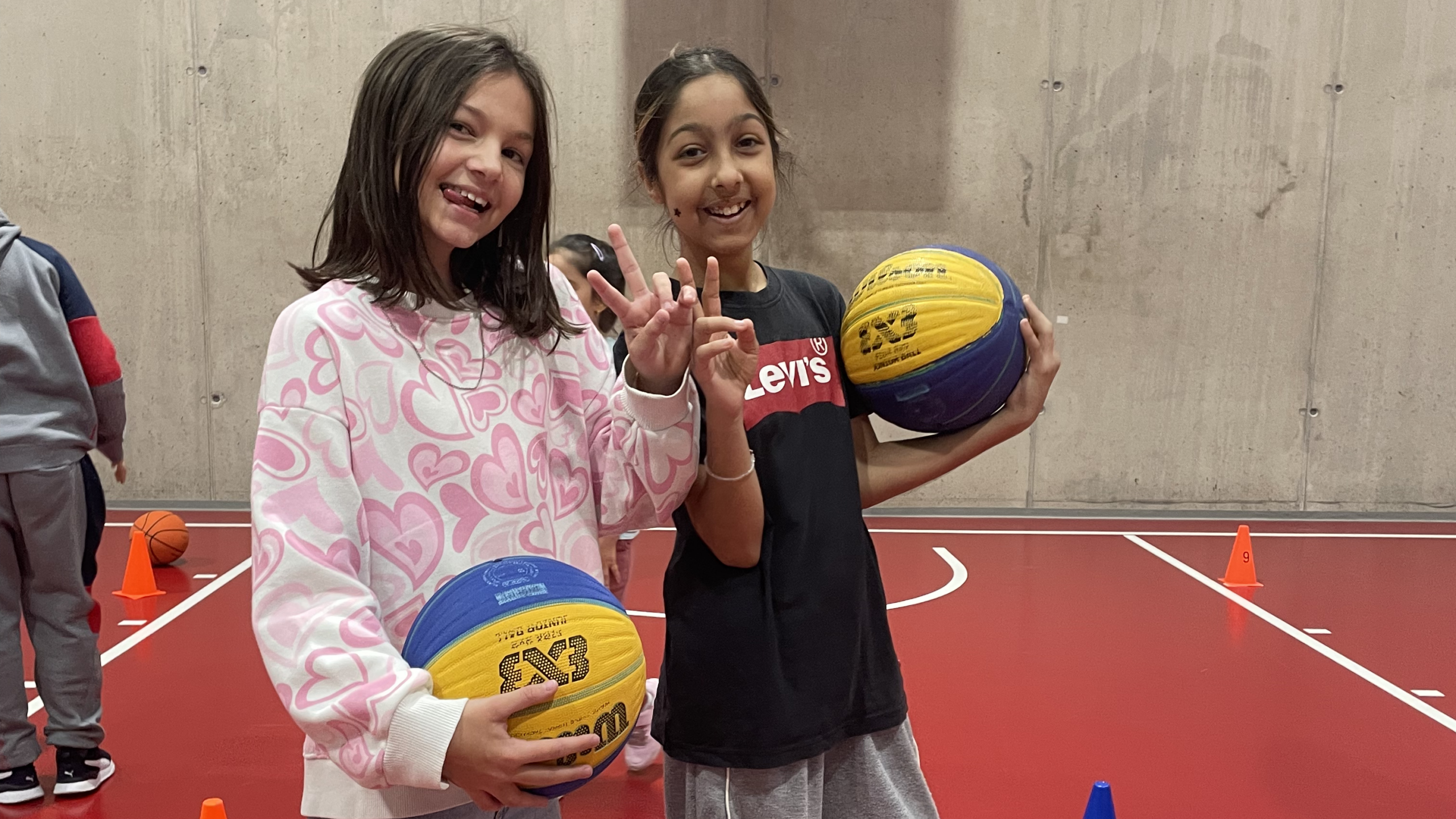 Zwei Mädchen posieren mit einem Basketball.