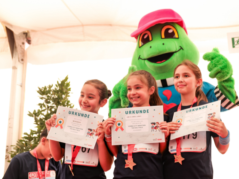 Drei Mädchen posieren mit dem Maskottchen Hopsi Hopper und ihren Urkunden.