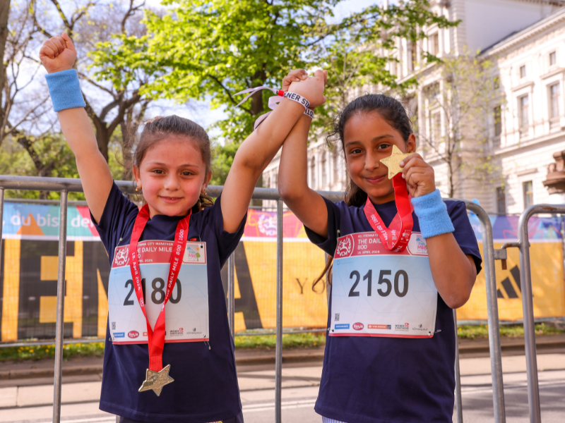 Zwei Mädchen posieren lächelnd mit ihren Medaillen.