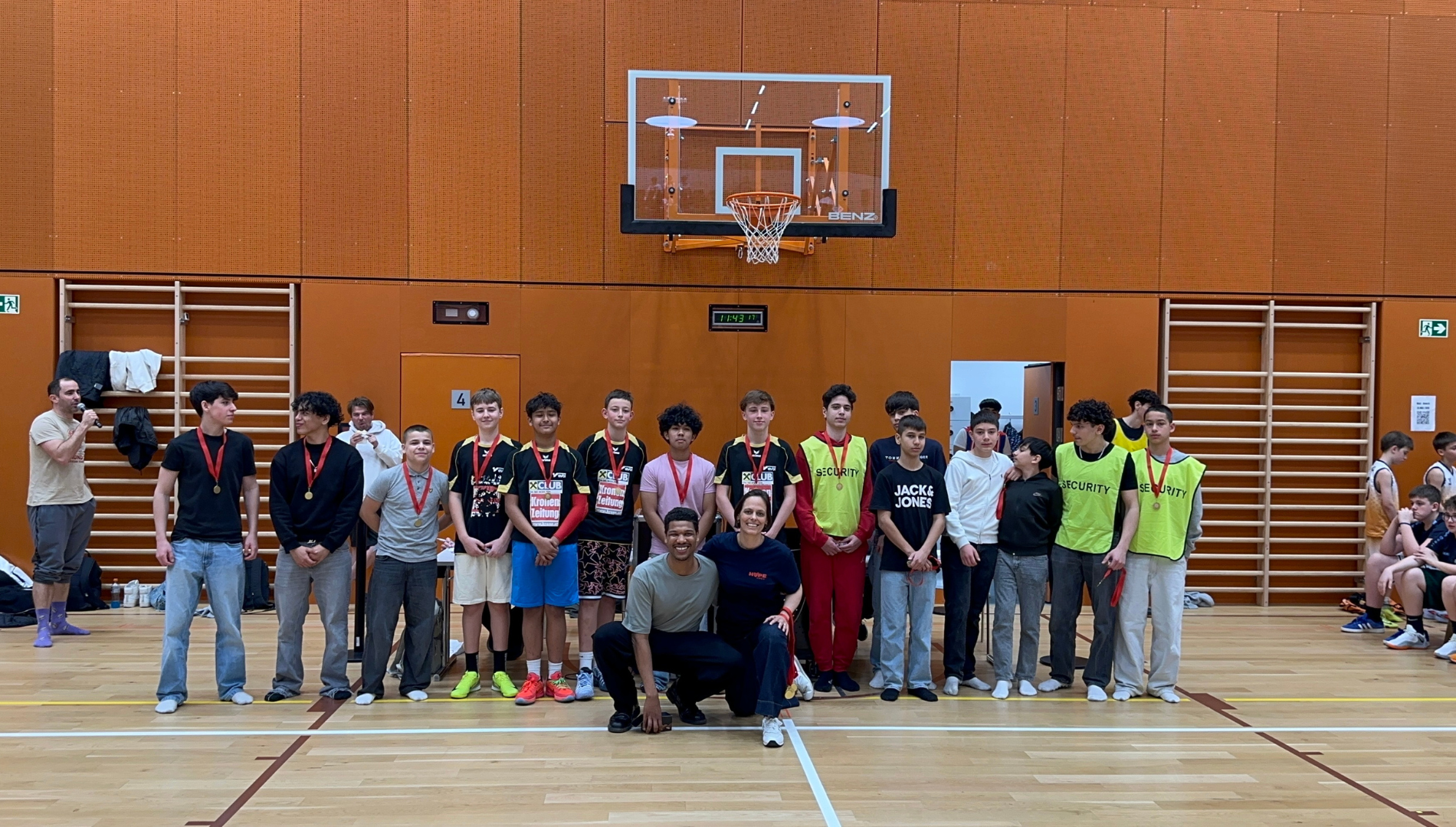 Ein Gruppe Schüler posiert auf einem Basketballfeld in einer Sporthalle.