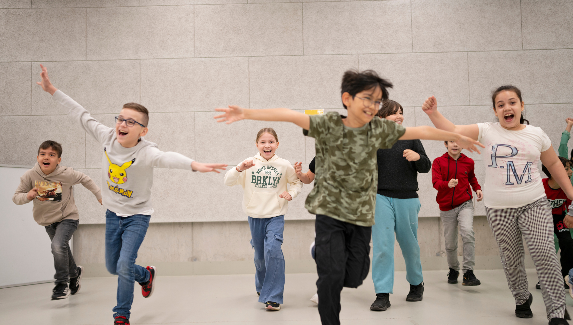 Eine Gruppe von Kinder läuft auf einer Airtrack Matte und lacht dabei.