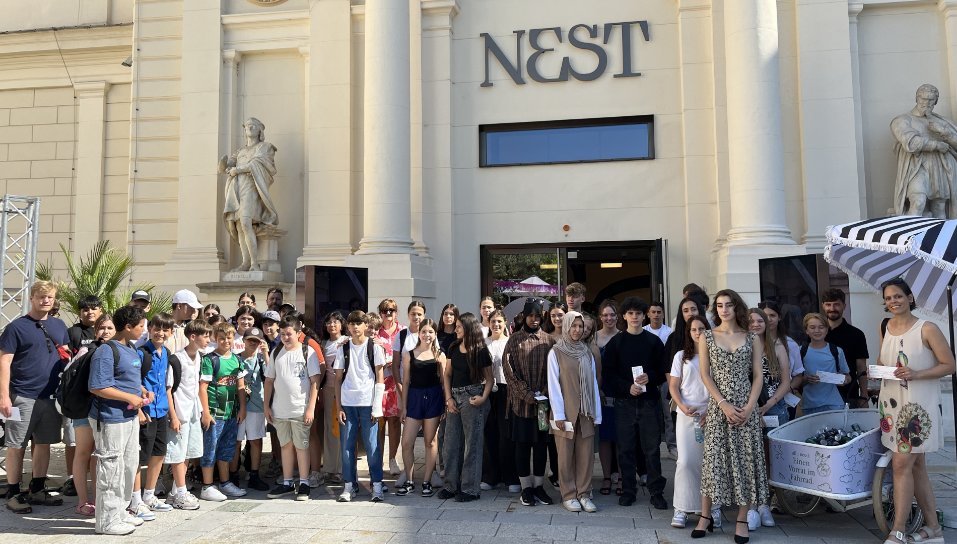 Eine Gruppe von Mittelschüler:innen posiert vor dem Eingang zum NEST.